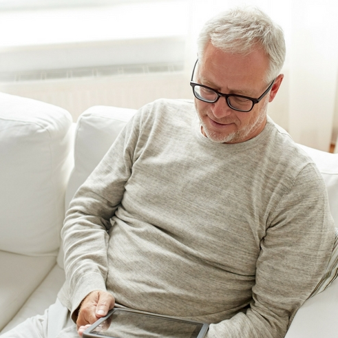 man on tablet couch